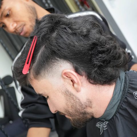 Barber shaping a haircut with comb and clippers