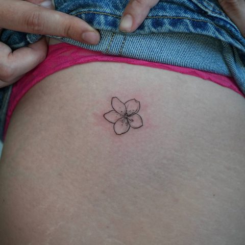 Fine line frangipani tattoo on a hip