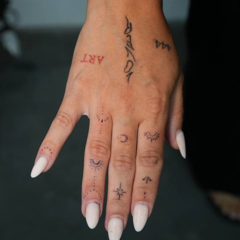Tiny fine line tattoos across a hand and fingers