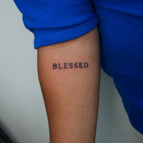 Blessed lettering tattoo on an arm