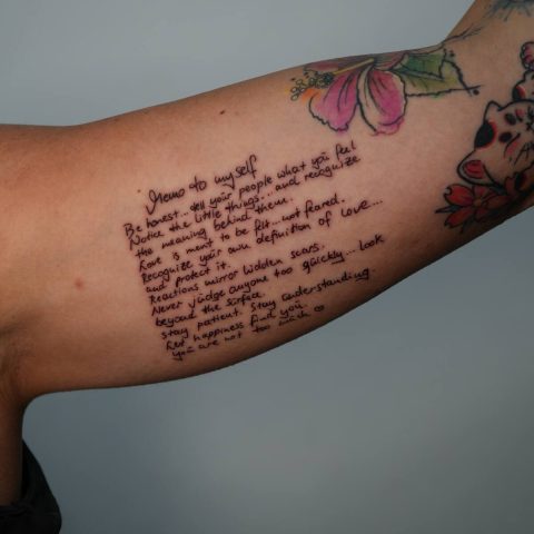 Long script quote tattooed down an arm