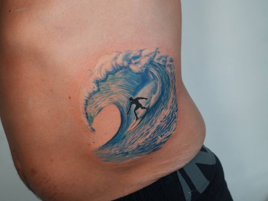 Full colour wave and surfer tattoo on a ribcage